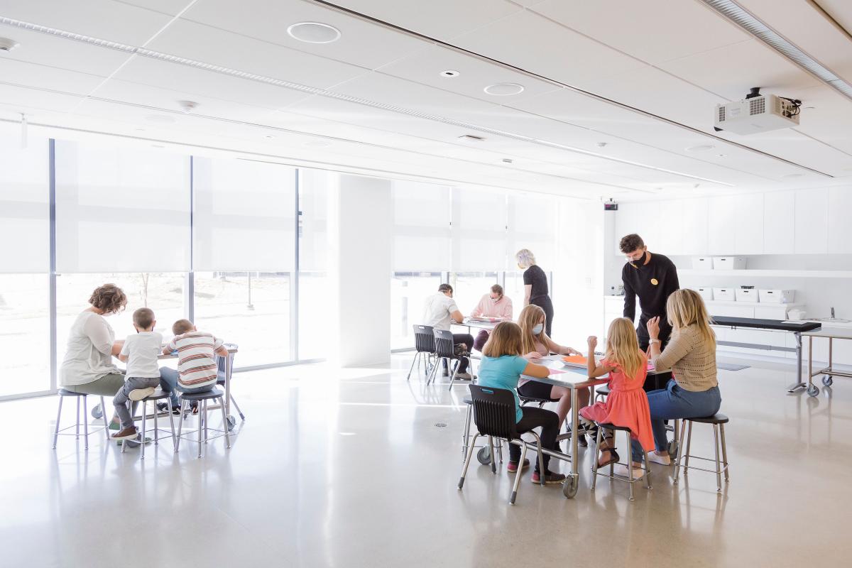 Remai event - tables with kids and two adults watching