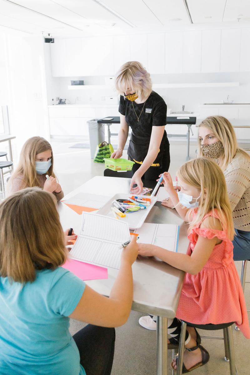 Remai event - table with kids drawing and two adults supervising